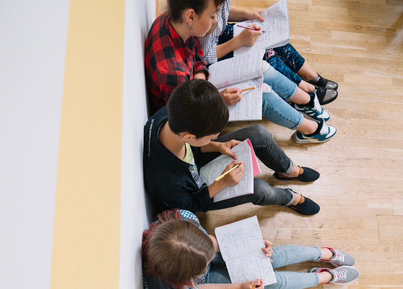 Estudantes sentador no são escrevendo em seus cadernos.